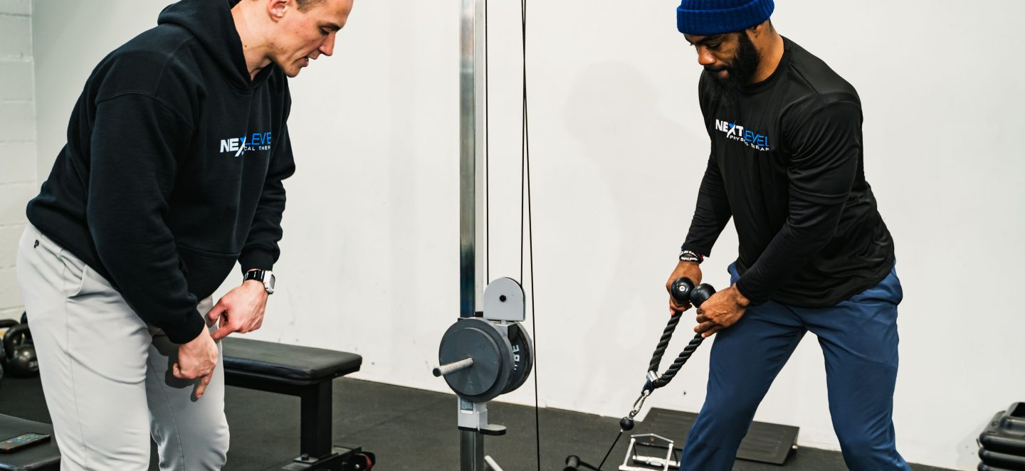 Physical therapist coaching a patient through a cable exercise at Next Level Physical Therapy in Southampton, PA