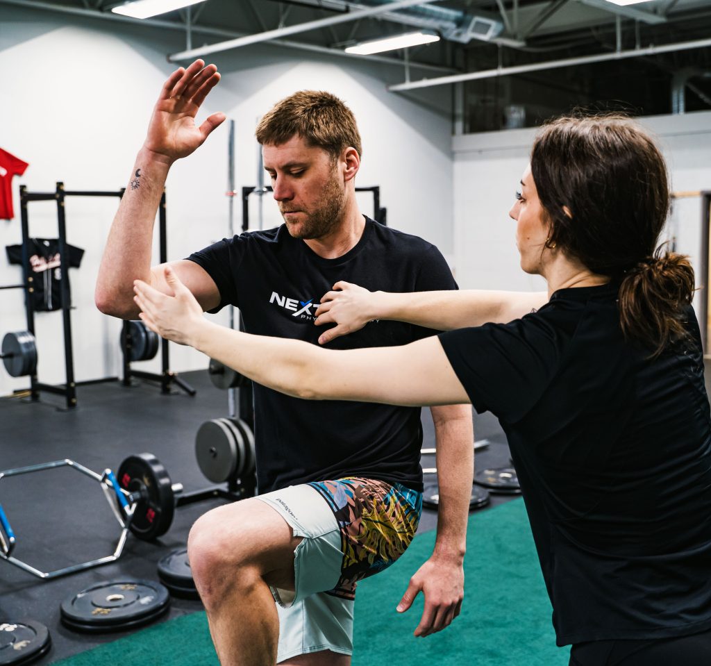 Physical therapist working with a patient as he performs a knee raise movement at Next Level Physical Therapy in Southampton, PA