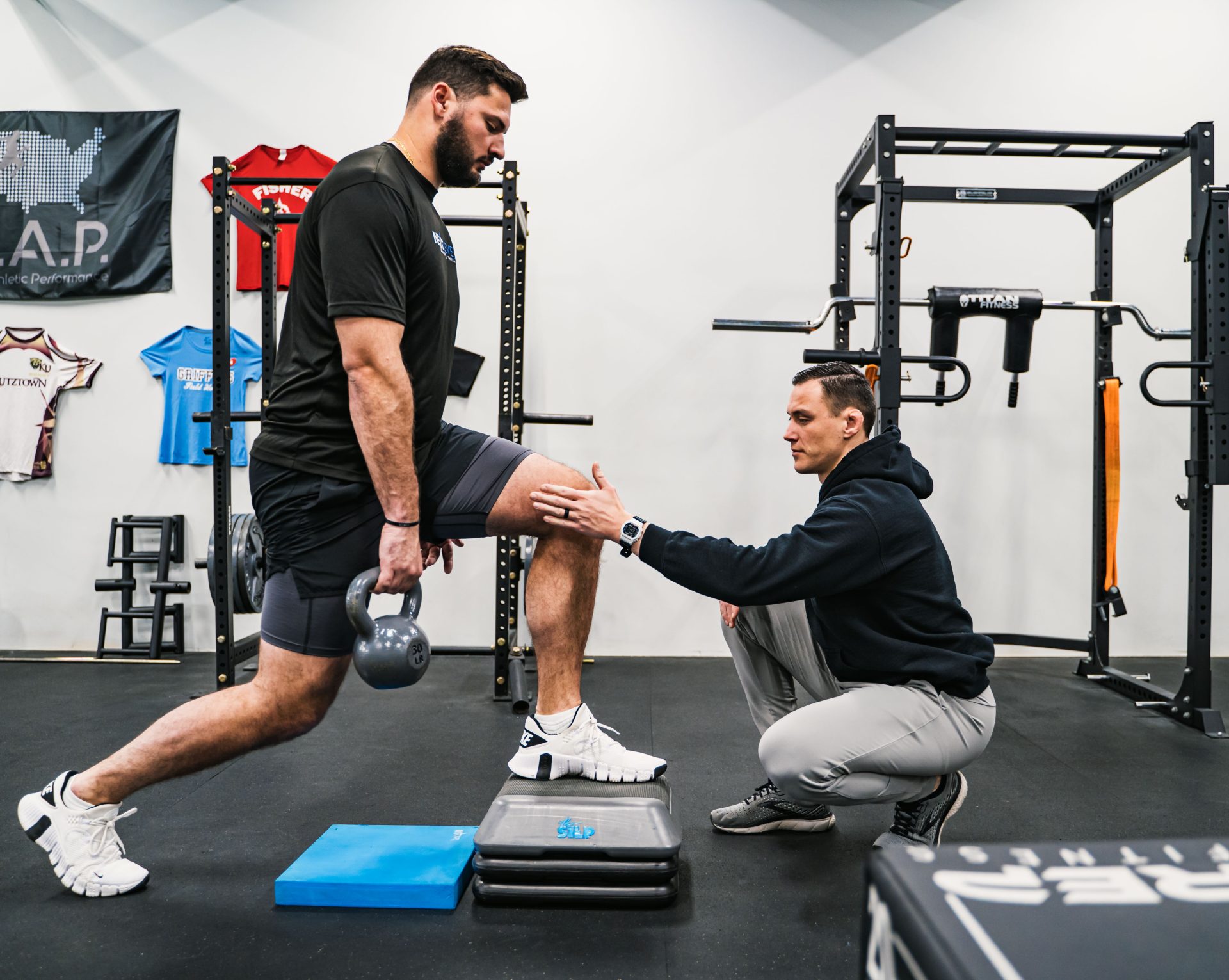 Physical therapist coaching an athlete through a split-stance exercise during ACL injury recovery