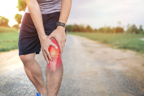 Man outside holding his knee in pain from exercising
