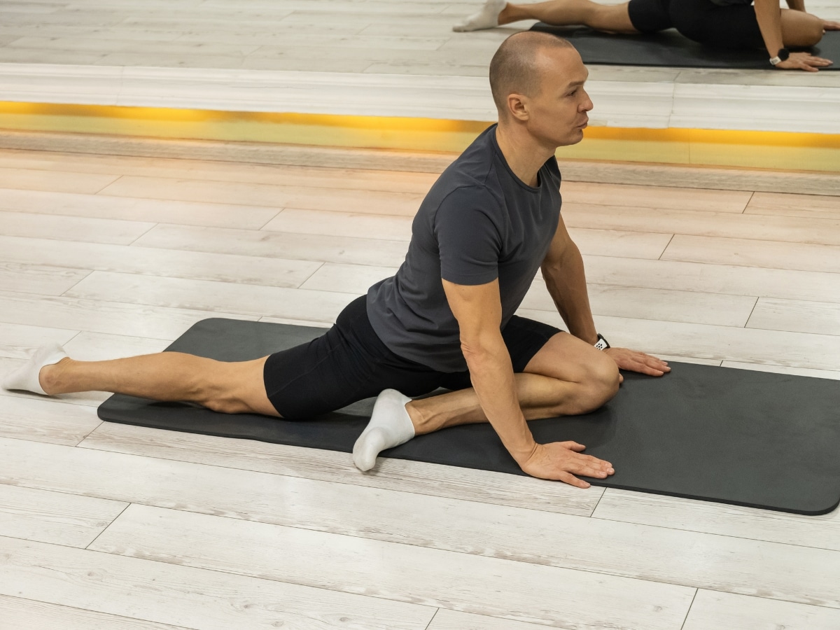 ACTIVE ADULT PERFORMING HIP MOBILITY DRILL ON FLOOR and MAT