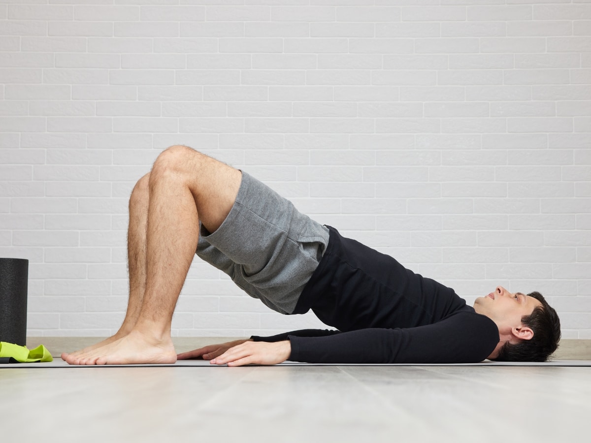 ATHLETE PERFORMING CONTROLLED REHAB EXERCISE GLUTE BRIDGE