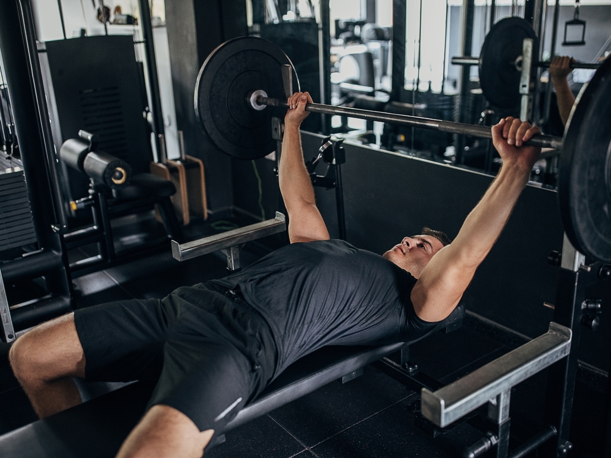 ATHLETE SETTING UP FOR BENCH PRESS WITH EMPHASIS ON SHOULDER BLADE AND RIB CAGE POSITION