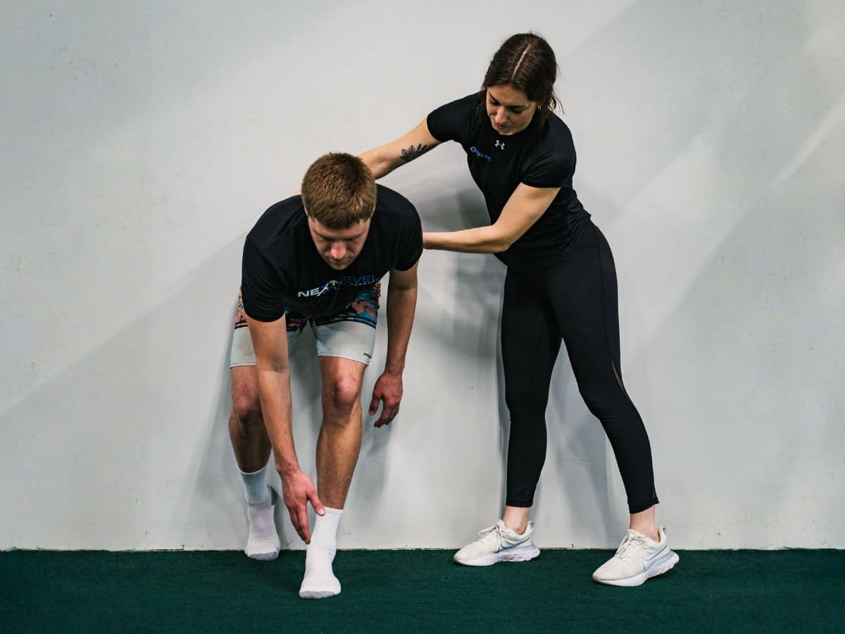 PHYSICAL THERAPIST COACHING PATIENT THROUGH HIP HINGE FOR LOWER BACK PAIN