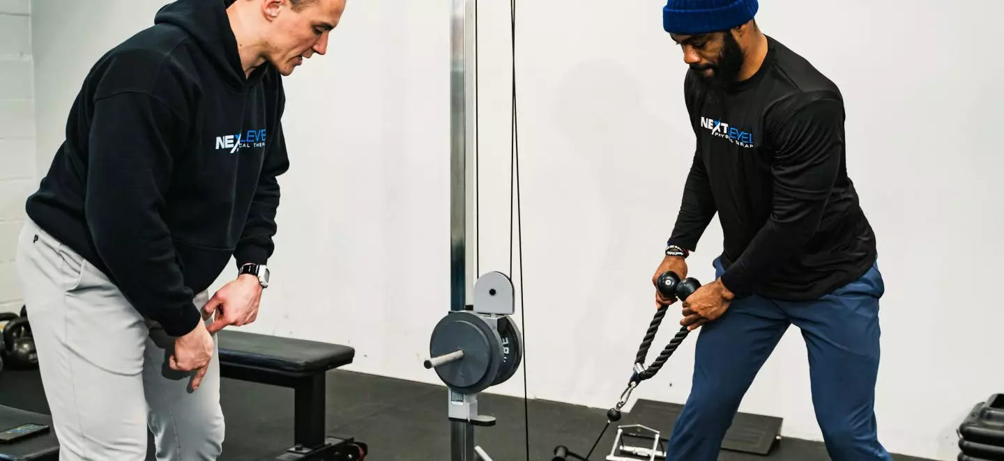 Physical therapist coaching a patient through a cable exercise at Next Level Physical Therapy in Southampton, PA